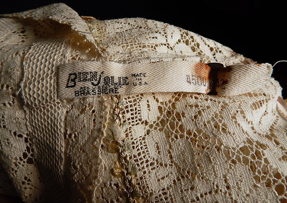 Vintage Bien Jolie Brassiere White Filet Lace Rosette Camisole Bra Bandeau Top
There is a "Bien Jolie Brassiere Made in U.S.A." Size 42 stamped label strap hanging down the front. The bra measures 18 inches long, with a 36 inch bust and 36 inch waist. It is in good as-is condition, with some frays along the ribbon shoulder straps. This is truly a wonderful piece of wearable lingerie art!