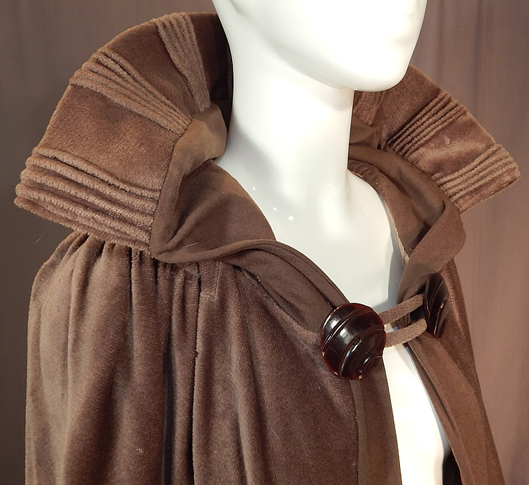 Vintage Art Deco Khaki Brown Mohair Wool Winter Shawl Collar Cloak Cape
This wonderful winter cloak cape is a long full floor length, with a wide shawl collar mixed with wool and pleated ribbed trim accents, two large carved celluloid brown button toggle closure on the front neck and is fully lined with a grayish taupe color silk lining and arms straps sewn inside. 