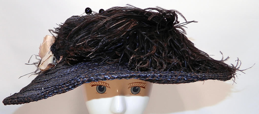 Edwardian Woven Black Straw Ostrich Feather Wide Brim Hat & Hatpins. It is made of a woven black straw basket weave, trimmed with black ostrich feathers and a silk flower on the side.