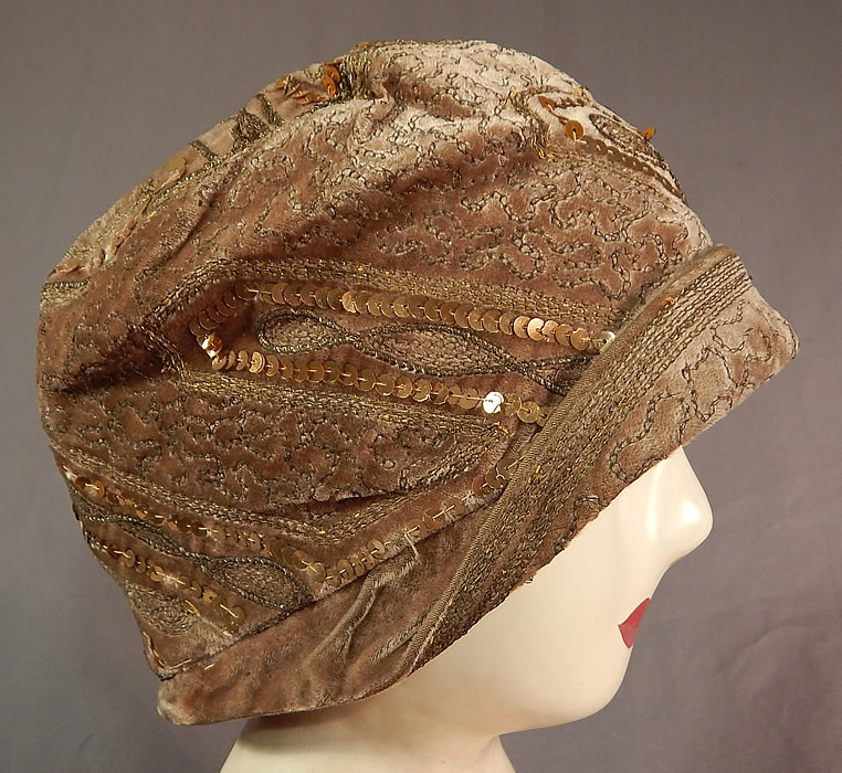 Vintage Art Deco Gold Lamé Embroidery Sequin Beaded Flapper Cloche Hat
The hat is made of a beige taupe color velvet fabric, with gold metallic lamé chain stitching embroidery work and gold metallic sequin beading all done in decorative geometric zigzag designs. 
