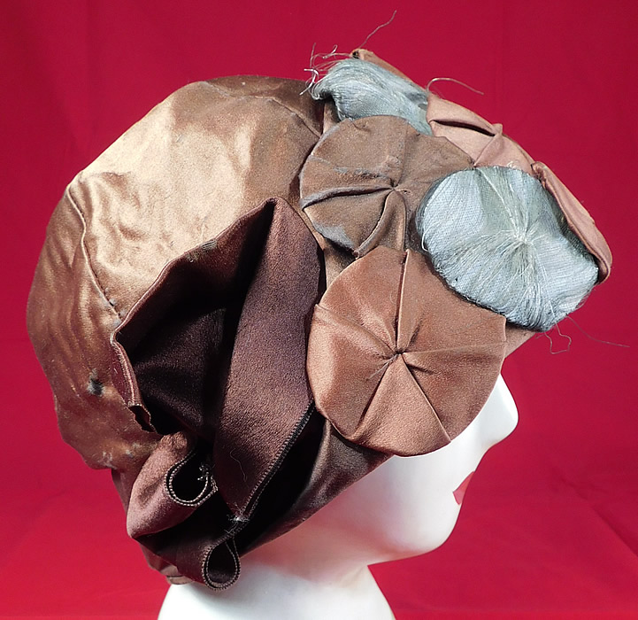 Vintage Fashion Hat Art Deco Brown Silk Silver Lame Rosette Flapper Cloche
This fabulous flapper cloche hat has a form fitting brimless toque style, with brown silk ribbon bow trim along the side and is fully lined with a "Fashion Hat Paris New York" label inside. 