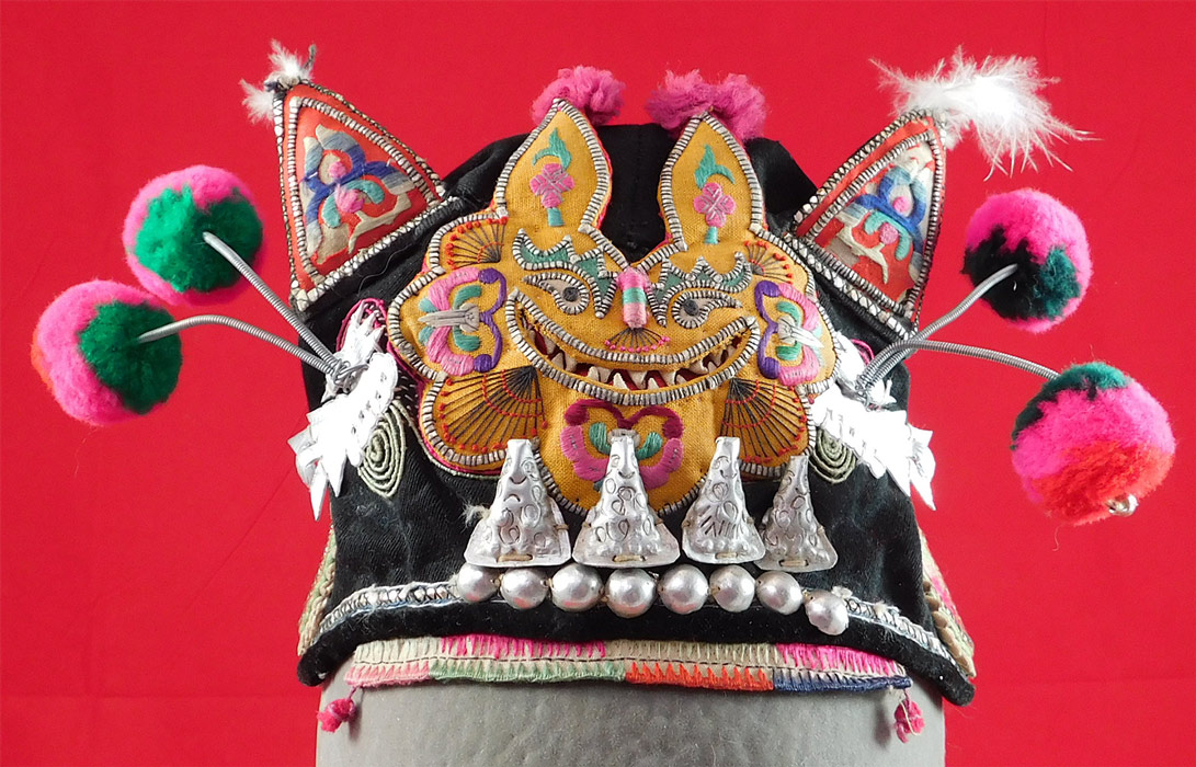 Antique Chinese Bai Miao Minority Childrens Festival Embroidered Tiger Wind Hat
This charming child's wind hat has yin and yang symbols, peony flowers, pheasant bird embroidered roundels medallion appliques on the sides and back with silver bells hanging down on chains, an open top crown and is fully lined with a colorful floral print cotton fabric inside.