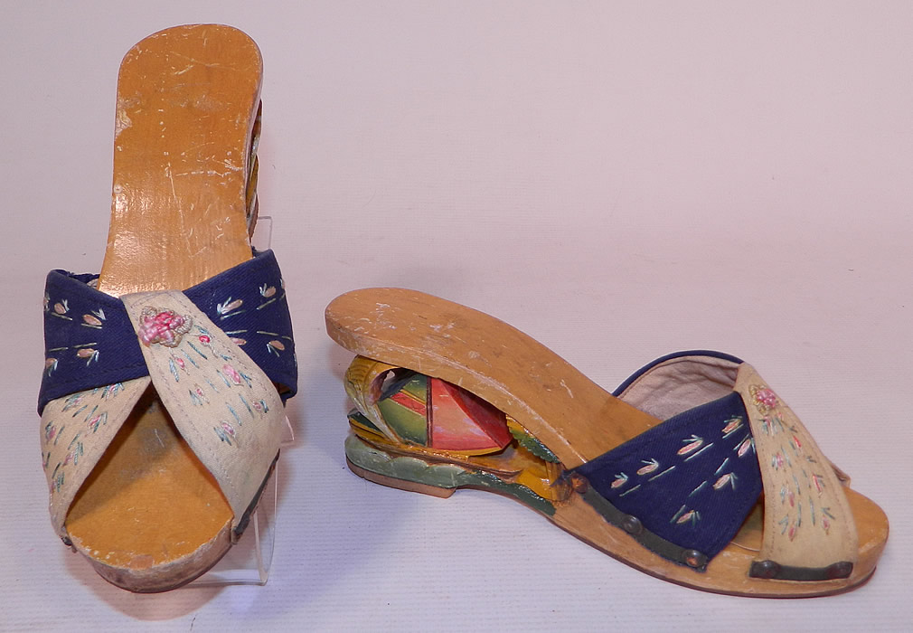 Vintage Philippines Hand Painted Carved Wooden Wedge Sailboat Mules Sandal Shoes
This pair of vintage Philippines hand painted carved wooden wedge sailboat mules sandal shoes date from the 1940s. They are made of a hand painted carved wood, with a cut out sailboat ocean waves design on the heels and hand embroidered blue and white fabric criss-crossing across the instep front vamp.