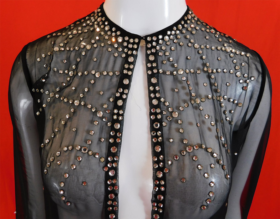 Vintage Art Deco Style Sheer Black Rhinestone Beaded Glitzy Evening Coat Jacket
This glamorous glitzy evening jacket has a long mid length loose fitting style, with an open front, hook closure at the neck, long full sleeves with snap closures at the cuffs and is sheer, unlined. 