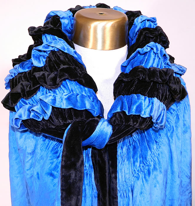 Vintage Gatsby Blue & Black Velvet Reversible Fringe Cocoon Opera Cloak Cape. This gorgeous long opera cloak cape is loose fitting with a cocoon wrap style, matching velvet fabric neck tie closure and large shawl style collar. The cape measures 40 inches long, with 20 inch long fringe and is 70 inches in circumference. It is in excellent condition. This is truly a wonderful piece of wearable art! 