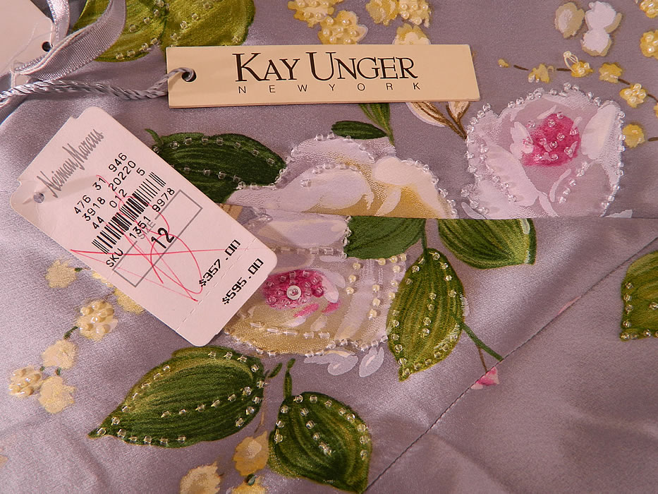 Kay Unger New York Silver Silk Beaded Rose Flowers Strapless Evening Gown. There is a "Kay Unger New York" designer label size 12 and Neiman Marcus store tags with the original price tag of $595.00 attached. The dress measures 55 inches long, with 44 inch hips, a 38 inch waist and 40 inch bust. It is in excellent unworn condition, NWT.