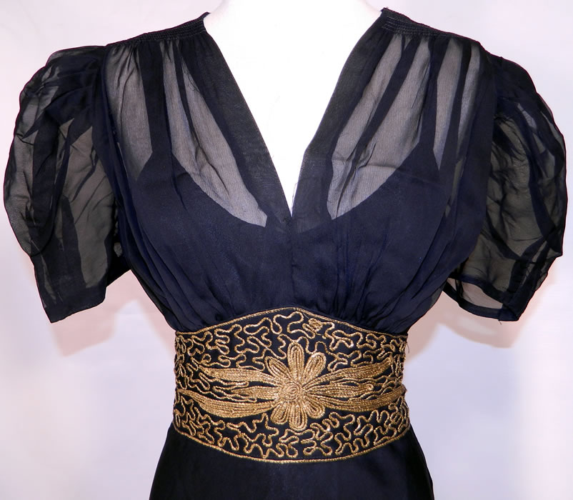 Vintage Black Silk Chiffon Gold Lamé Soutache Belted Evening Gown Dress & Slip. This gorgeous gown has a long floor length skirt, is sheer, unlined, with short puffy sleeves, smocking along the shoulders, a V front neckline, an attached cummerbund sash belt with button back and side zipper closure.