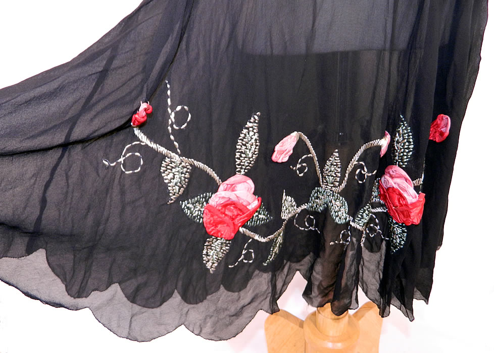 Vintage Black Silk Chiffon Red Roses Ribbon Rosette Trim Drop Waist Dress. This fabulous flapper dress has a loose fitting drop waist style, scalloped hemline skirt, short sleeves, side snap closures and is unlined. The dress measures 40 inches long, with a 32 inch waist, 38 inch bust and 16 inch back.