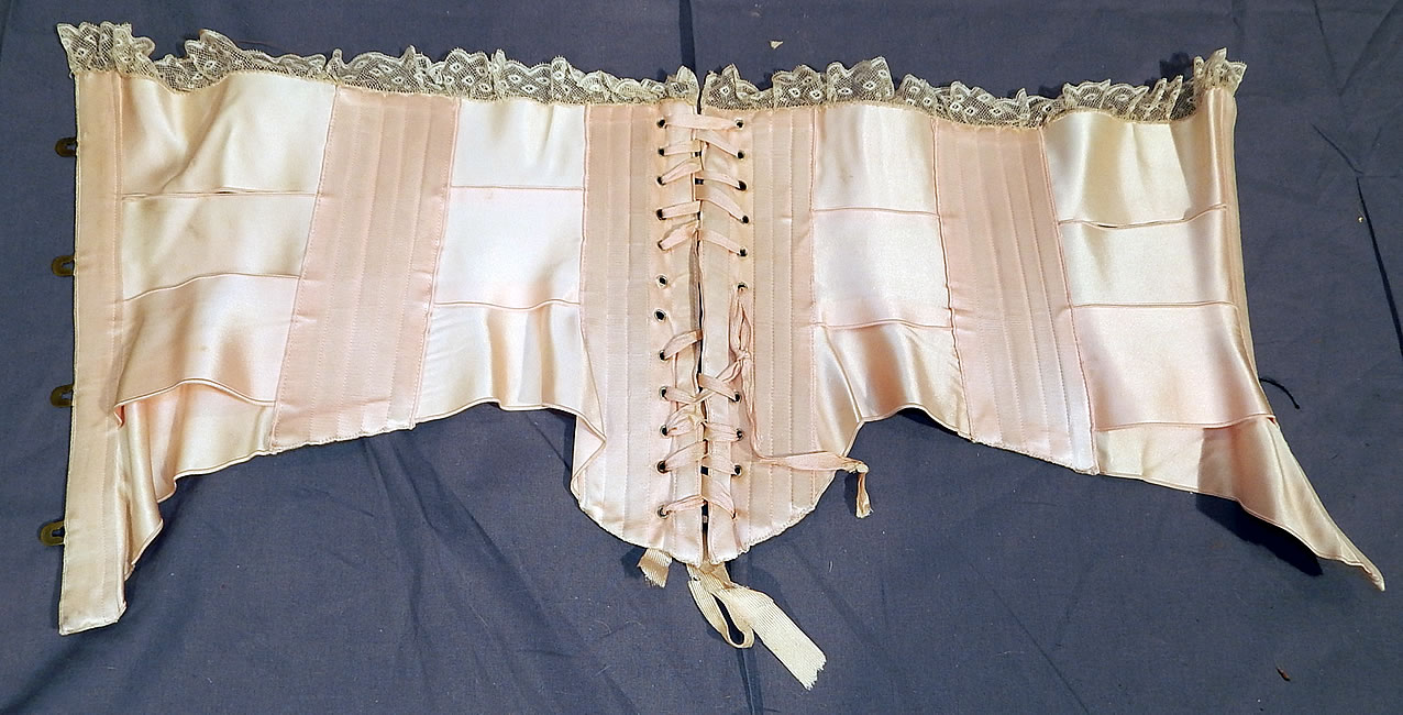 Victorian Antique Lace Trim Pink Silk Ribbon Short Negligee Night Corset Waist Cincher
The corset measures 11 inches long in the front, 9 1/2 inches long in the back, 7 1/2 inches long on the sides, with a 23 inch waist which is adjustable. It is in good condition, with only some fraying of the original silk corset strings lacing. This is truly a rare and wonderful piece of wearable antique corsetry lingerie art!