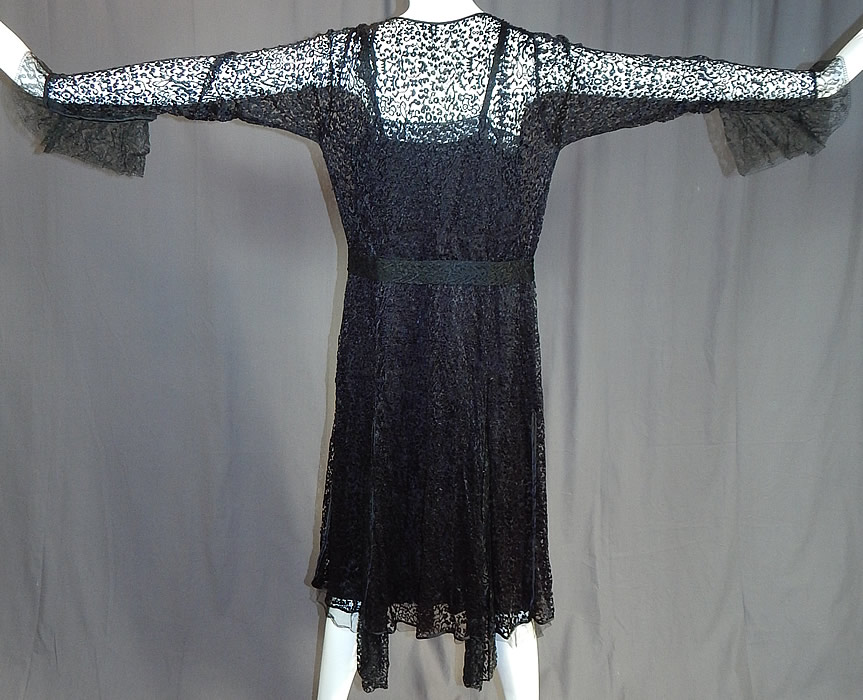 Vintage Art Deco Buckle Belted Black Silk & Chantilly Lace Flapper Dress
This fabulous flapper dress has an open front low V neckline, with black silk slip lining inside which has black Chantilly lace trim edging along the top and bottom, a lace belt with Art Deco style rhinestone buckle clasp at the waist, long tapered sleeveless with flared gauntlet cuffs, an uneven handkerchief skirt hemline and snap closures along the side of the slip.