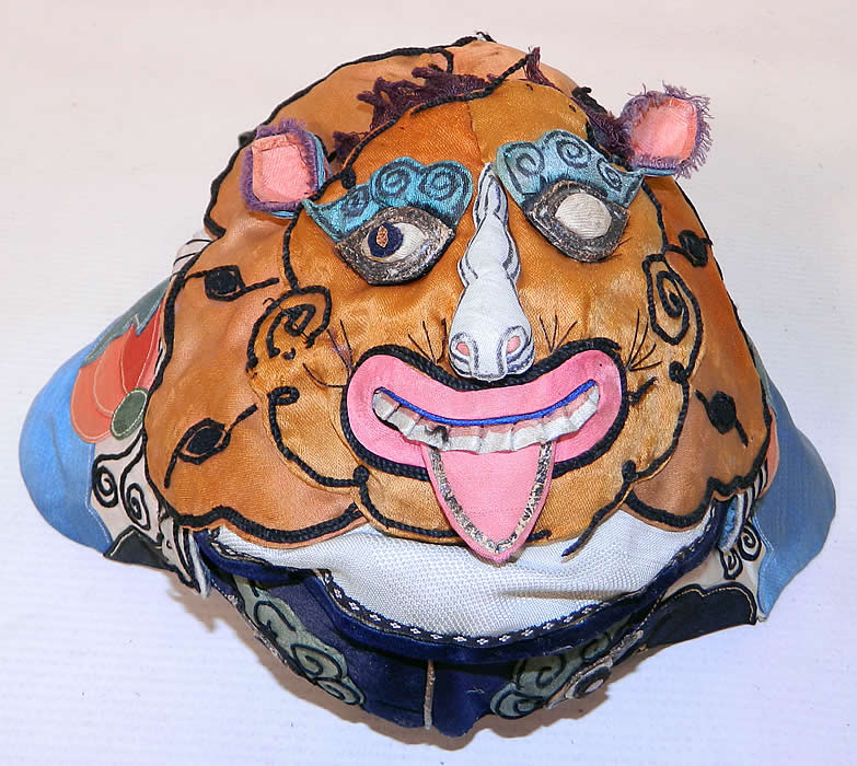 Antique Chinese Child Infant Silk Applique Tiger Wind Hat. The hat measures 18 inches long and 16 inches in circumference around the face. It is in good condition, with only minor wear to the silk fabric, some loose trim and is missing a pupil eye 