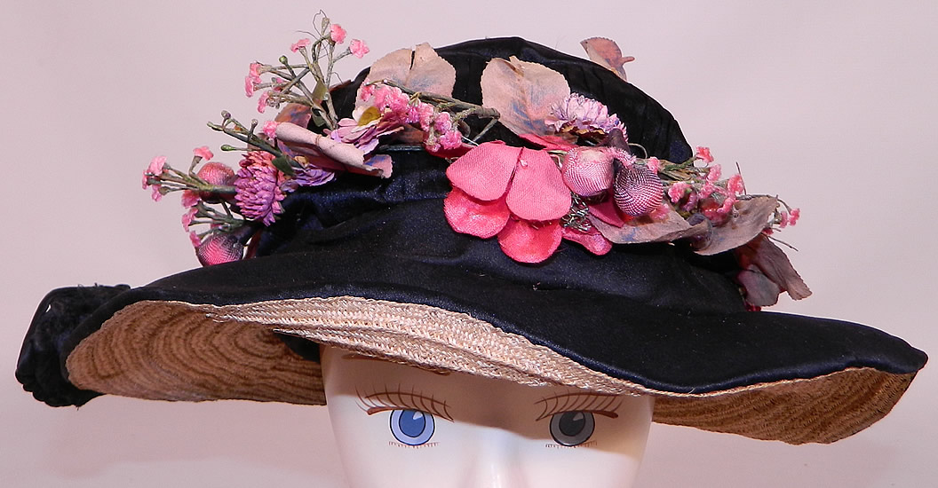 Edwardian Black Silk & Natural Straw Floral Garland Trim Wide Brim Hat. The hat is made of a black silk fabric, with a woven natural straw brim underneath. There is black silk soutache ribbon work trim along the back, side and a pink flower leaf garland wreath trim hatband. 