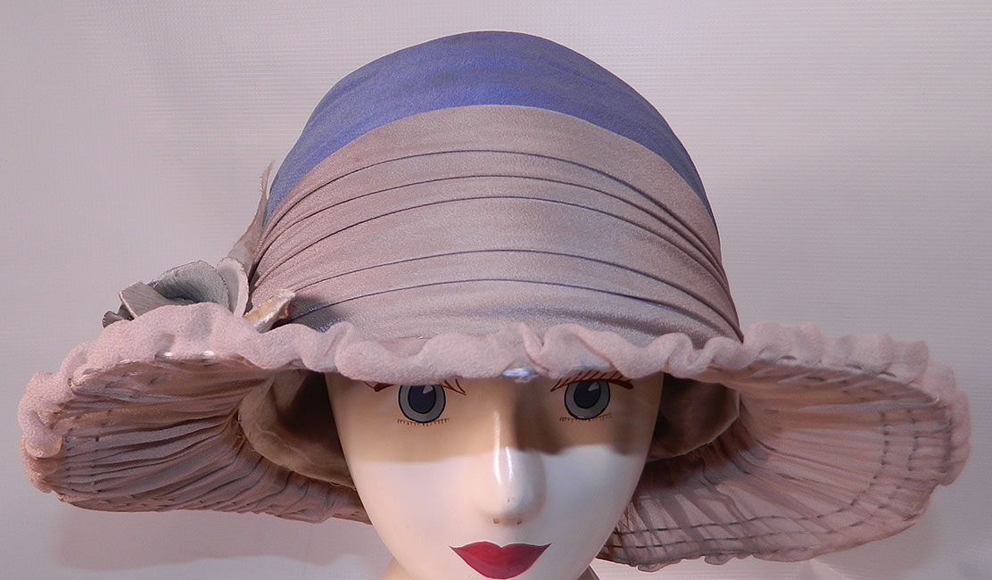 Vintage Maurice Importer Gray & Blue Silk Rose Flower Wide Brim Cloche Hat. It is made of a gray and blue silk fabric, with a blue velvet rose flower trim on the side.