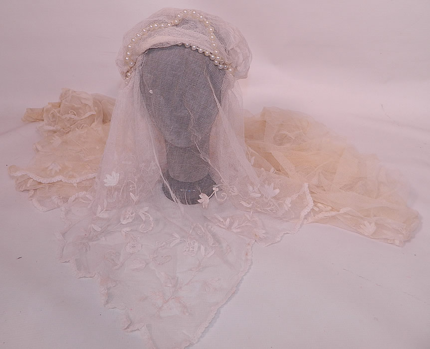 Vintage Pearl Beaded Cap Long Princess Lace Net Wedding Veil. It is made of an off white sheer net fabric with tape lace applique leaf flowers, tambour stitched embroidery work, lace trimmed scalloped hem and a pearl beaded cap.