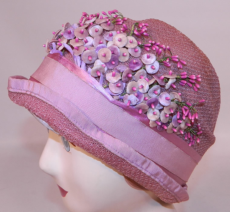 Vintage Tenne Hats Purple Lilac Woven Straw Lavender Flower Flapper Cloche. It is made of a pale purple lilac color woven straw fabric, with pink grosgrain silk ribbon trim edging around the brim, hatband and tiny velvet lavender flowers, blossoms trimming the front.