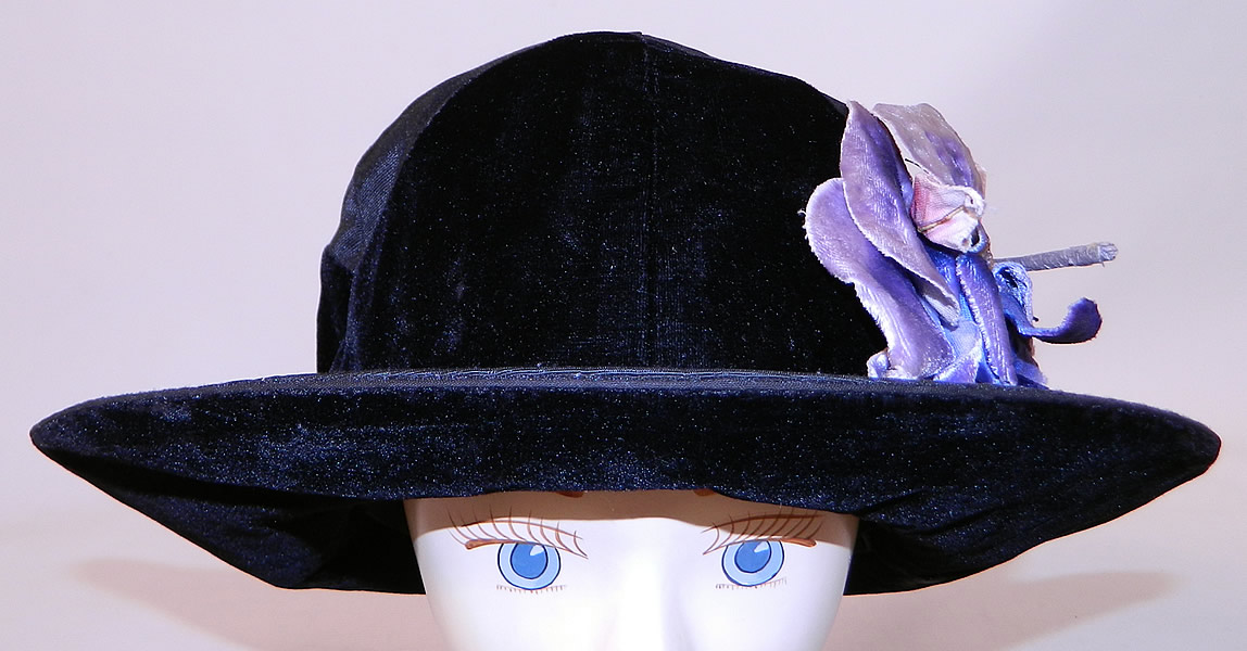 Vintage Hart Hats Black Silk Velvet Wide Brim Purple Flower Flapper Cloche Hat
This fabulous flapper cloche style hat has a form fitting style with an upturned wide brim which is wider on the sides and front, backed in black velvet and is fully lined inside the crown in black silk with a "Hart Hats Cleveland, New York, Paris" label.