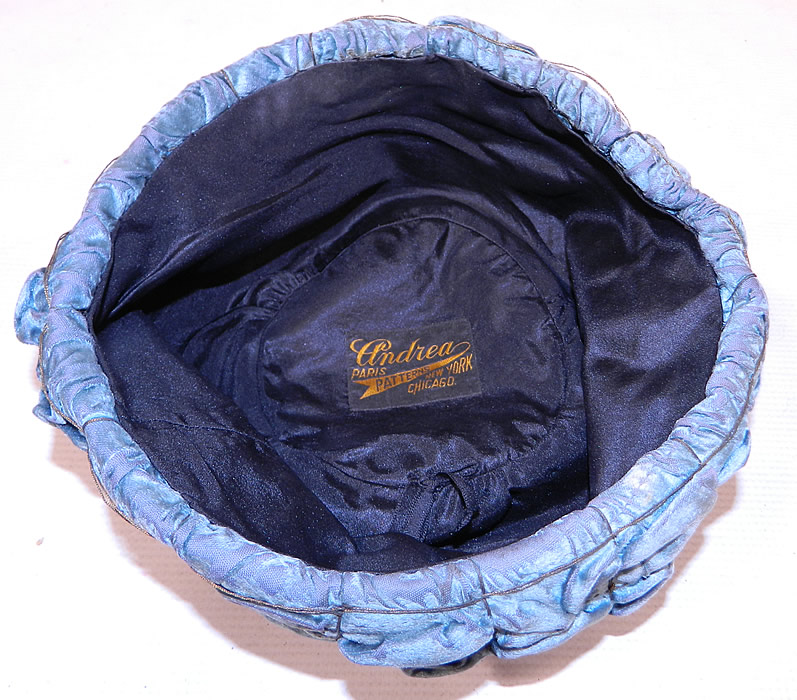 Vintage Ruched Cornflower Blue Gray Velvet Silver Lame Leaf Trim Toque Cloche Hat Lamé
This beautiful blue brimless toque style cloche hat is fully lined with a black silk fabric and a "Andrea Patterns Paris, New York, Chicago" label inside. 