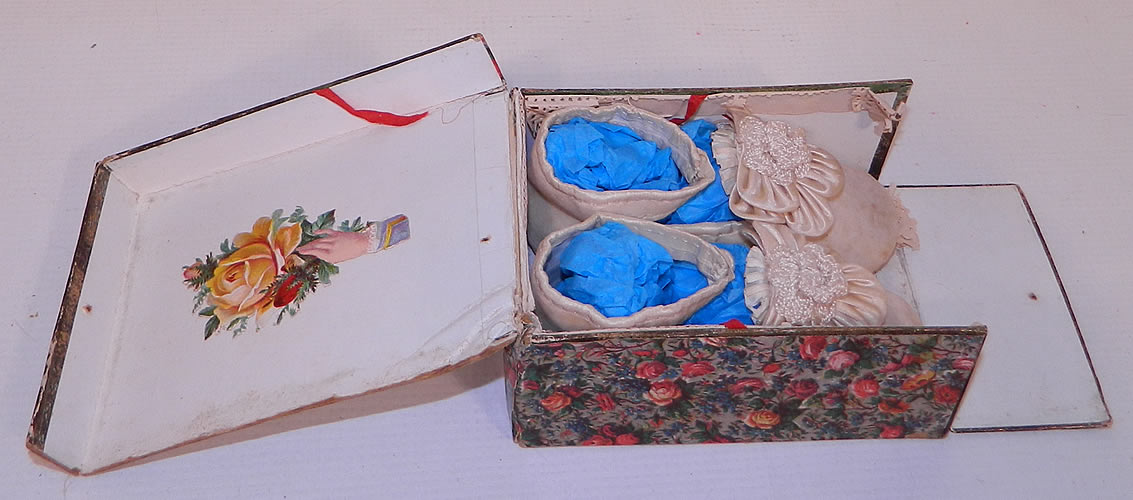 Victorian Antique White Velvet Rosette Maryjane Baby  Infant Shoes & Box. The shoes are in good condition with only some small faint age spotting and the box has some wear along the edges with paper loss. These sweet shoes would be great for display for a nursery or antique doll!