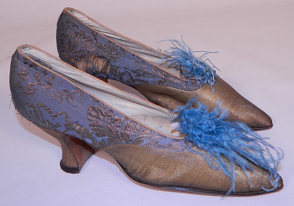 Edwardian Titanic Blue Silk Gold Lamé Damask Brocade Feather Trim Shoes. They are made of a blue silk damask, floral leaf brocade patterned gold metallic lamé fabric. These beautiful brocade fancy evening shoes have blue ostrich feather trim pompoms on the front instep vamps, a slip on style, with pointed toes and gold lamé covered French Louis XV spool heels.