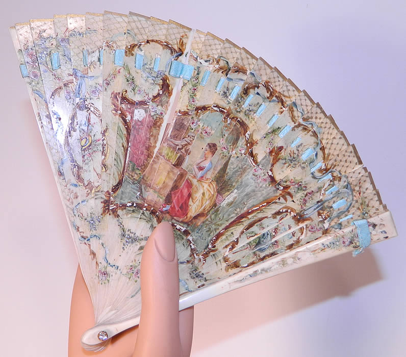 Victorian Antique Hand Painted Figural Bone Small Brise Dance Fan. It is made entirely of a carved bone sticks, with a hand painted 18th century figural floral design on the front, a blue ribbon bow floral garland design on the back and gold gilt accents. 