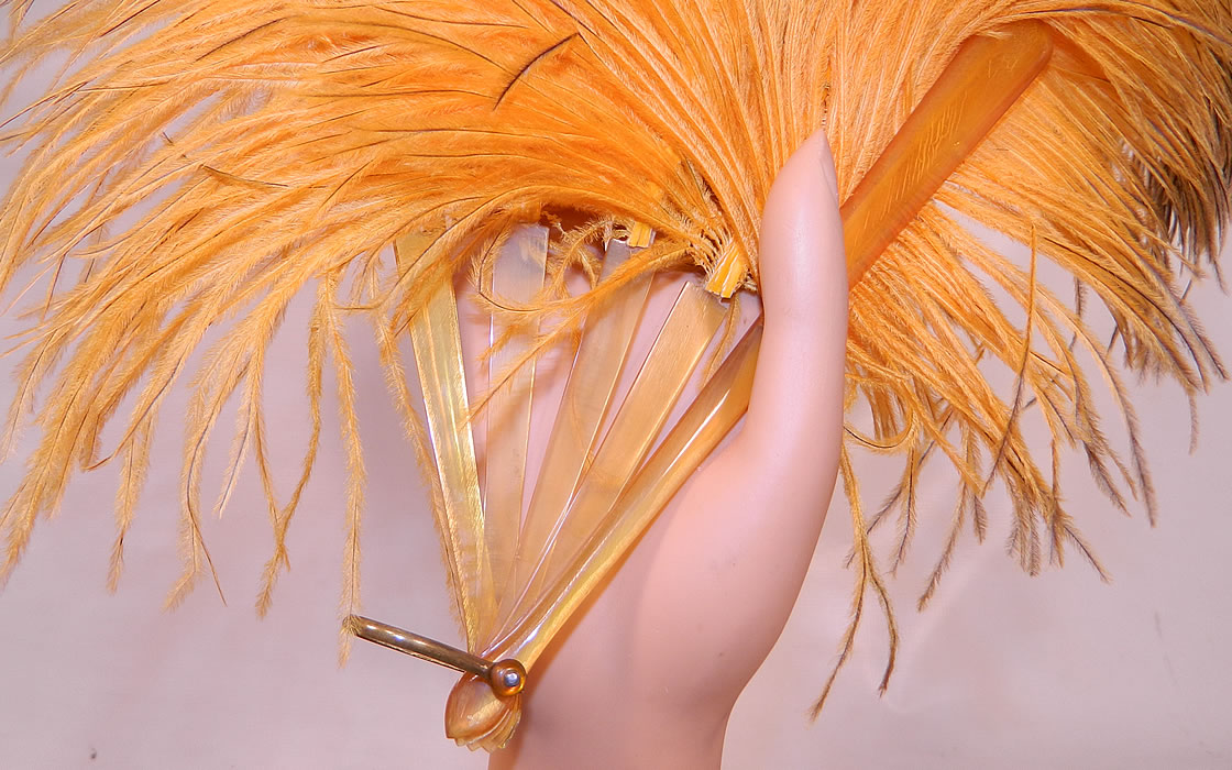 Vintage Golden Butterscotch Yellow Brown Tip Ostrich Feather Flapper Fan. There are five butterscotch yellow celluloid sticks and guards with a brass loop and rivet on the bottom.